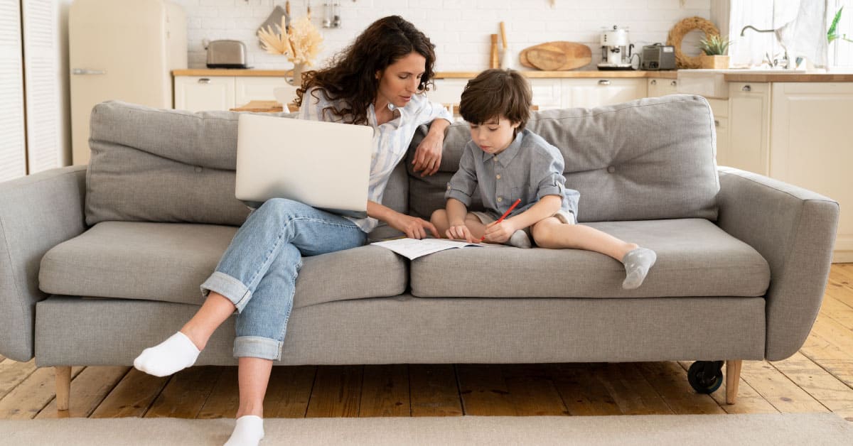 mother and son sitting on the couch while son does homework
